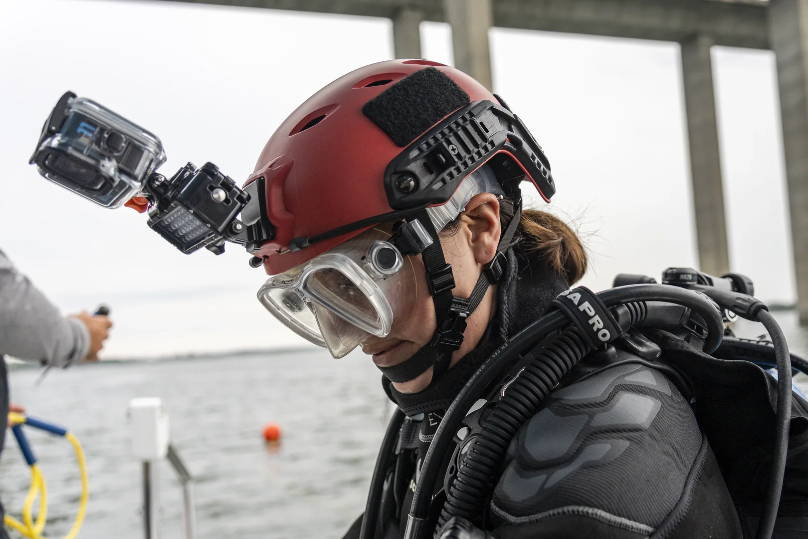 Andi Cross in diving gear with red helmet, dive mask, and camera equipment, preparing for underwater expedition