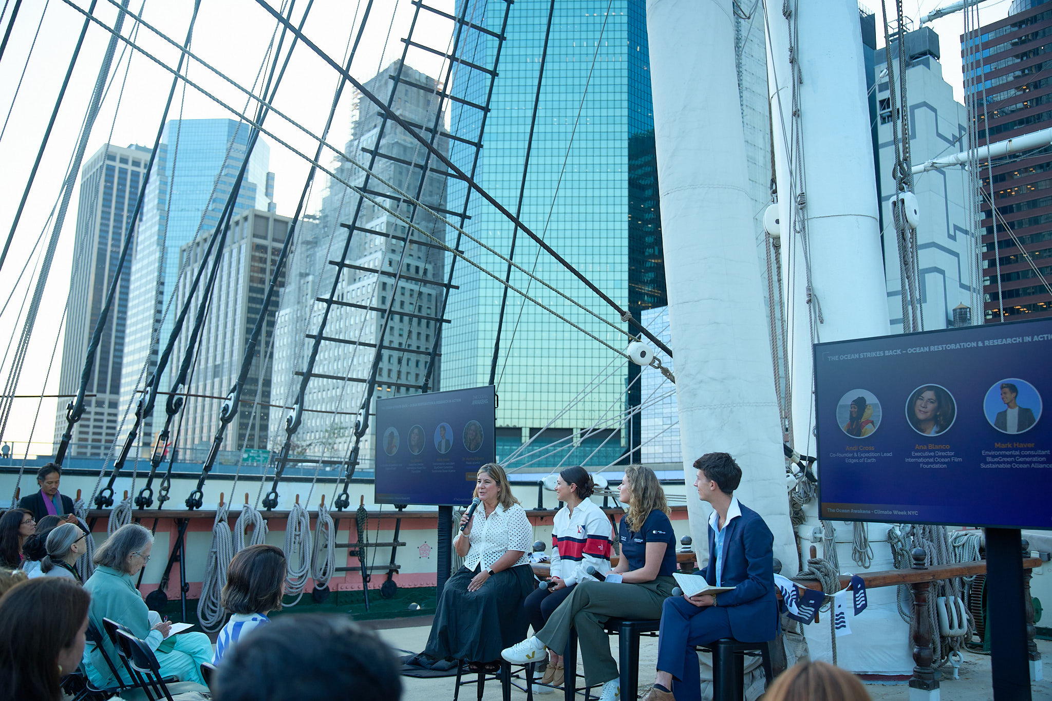 Ocean restoration panel discussion on boat deck with city skyline